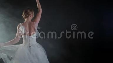 优雅的芭蕾舞演员穿着白色连衣裙，在黑暗中用<strong>灯光</strong>和烟雾舞蹈古典或现代芭蕾的<strong>元素</strong>